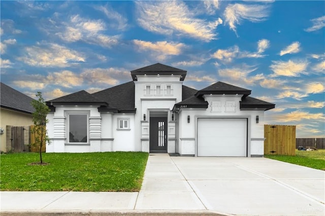 prairie-style home featuring a garage, stucco siding, a shingled roof, concrete driveway, and a front lawn
