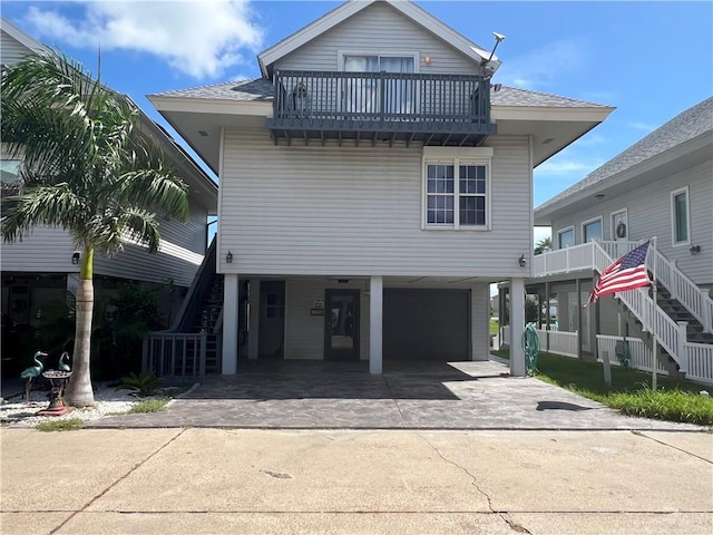 view of front of house featuring driveway, stairway, a carport, and roof with shingles