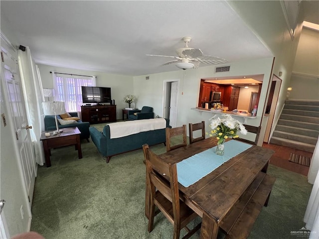 dining room with carpet floors, visible vents, stairway, and ceiling fan