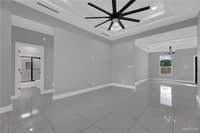 spare room featuring a raised ceiling and ceiling fan with notable chandelier