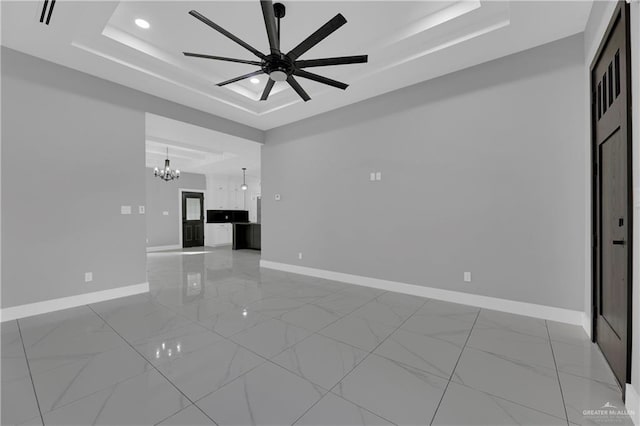 unfurnished living room featuring a raised ceiling and ceiling fan with notable chandelier