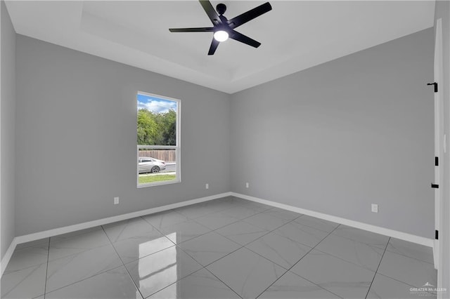 spare room with ceiling fan and a tray ceiling