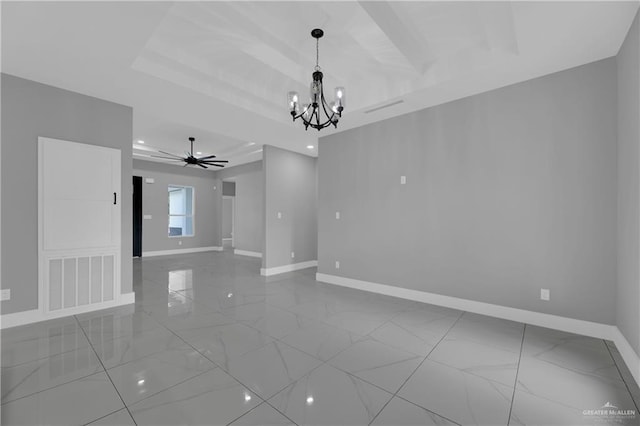 spare room featuring a tray ceiling and ceiling fan with notable chandelier