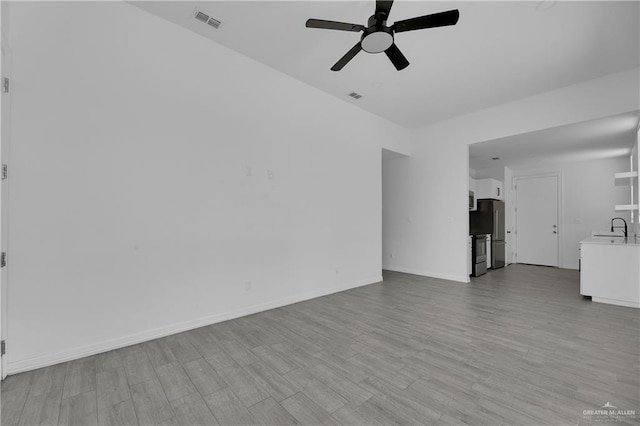 unfurnished living room with light hardwood / wood-style floors, ceiling fan, and sink