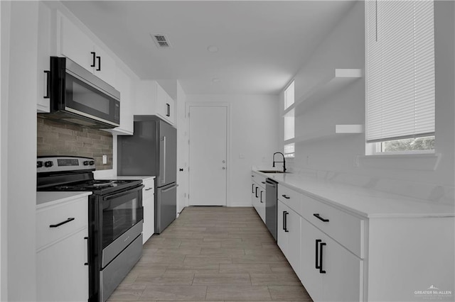 kitchen featuring sink, decorative backsplash, light hardwood / wood-style floors, white cabinetry, and stainless steel appliances