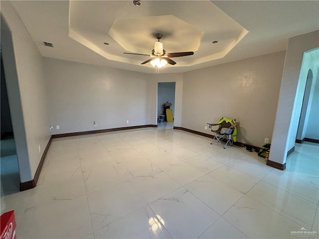 empty room with a raised ceiling and ceiling fan