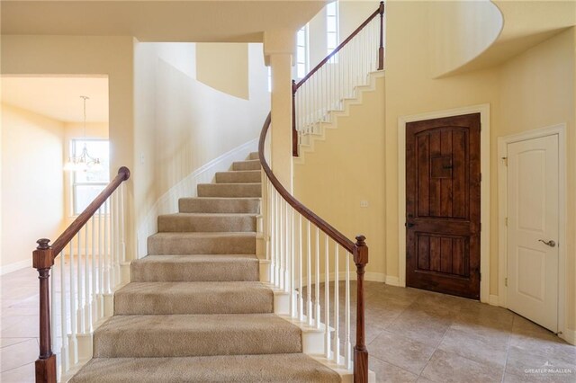 stairs featuring tile patterned floors, a high ceiling, and an inviting chandelier