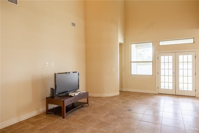 living room featuring french doors, light tile patterned flooring, and a high ceiling