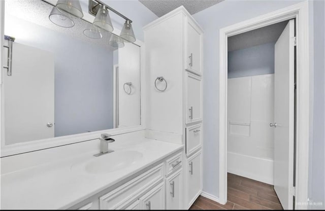 bathroom with hardwood / wood-style floors, vanity, a textured ceiling, and bathtub / shower combination