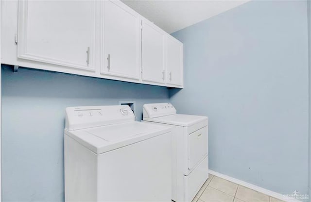 washroom featuring washer and dryer, cabinets, and light tile patterned flooring