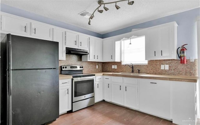 kitchen with hardwood / wood-style floors, black refrigerator, sink, electric range, and white cabinetry