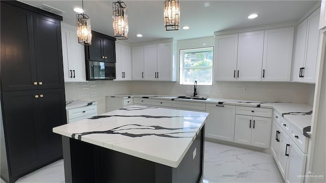 kitchen with recessed lighting, a sink, marble finish floor, light stone countertops, and stainless steel microwave