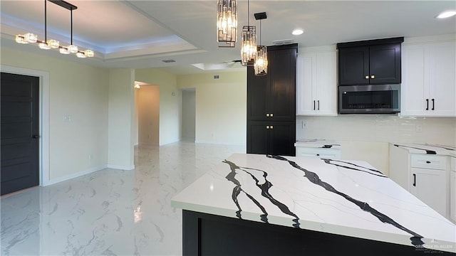 kitchen with light stone counters, marble finish floor, stainless steel microwave, open floor plan, and baseboards