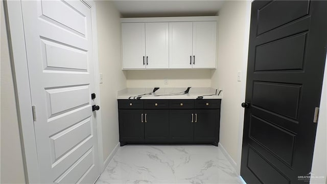 laundry area featuring marble finish floor and baseboards