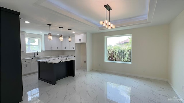 kitchen with a raised ceiling, a sink, marble finish floor, and baseboards