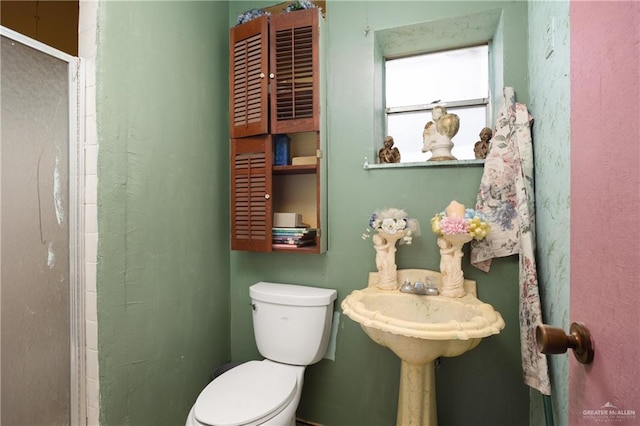 bathroom featuring toilet and a shower with shower door