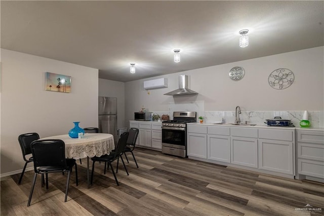 10766 N Minnesota Rd, Mission, TX 78574 - kitchen featuring stainless steel appliances, a sink, a wall unit AC, wall chimney exhaust hood, and wood finished floors