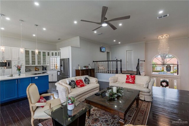 living room featuring ceiling fan with notable chandelier, dark hardwood / wood-style flooring, and ornamental molding