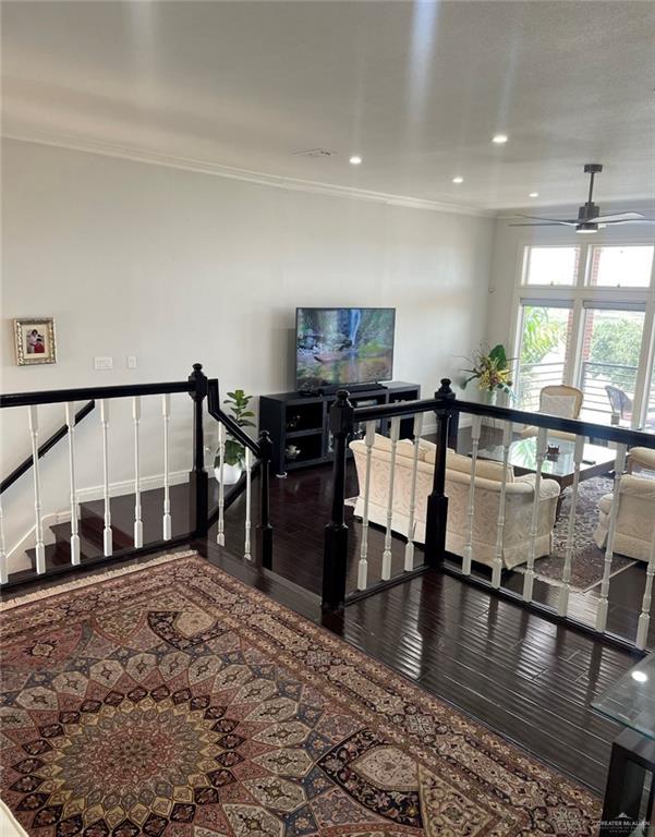 stairs with crown molding, ceiling fan, and hardwood / wood-style flooring