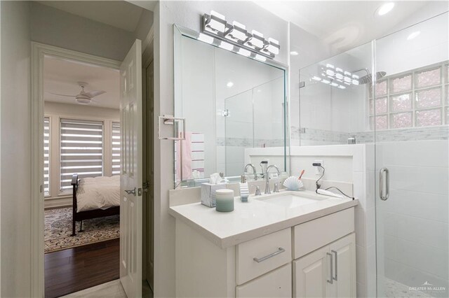 bathroom featuring wood-type flooring, vanity, a shower with door, and ceiling fan