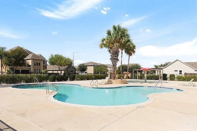 community pool with a patio, a residential view, and fence