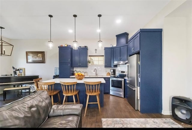 kitchen with under cabinet range hood, light countertops, a kitchen breakfast bar, stainless steel appliances, and blue cabinets