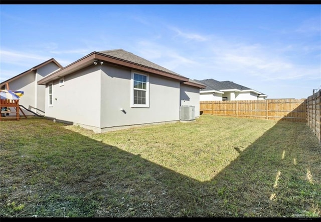 rear view of property with central air condition unit, a lawn, a fenced backyard, and stucco siding