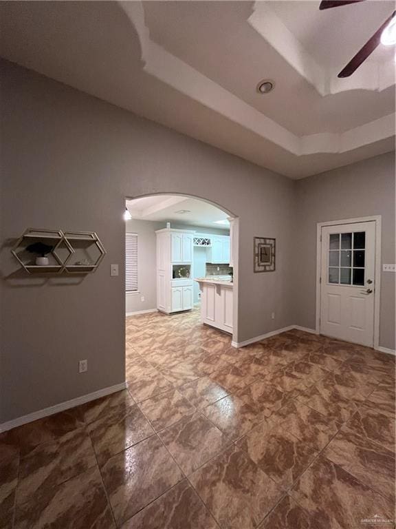 3404 Robin Ave, Pharr, TX 78577 - empty room featuring arched walkways, a ceiling fan, a raised ceiling, and baseboards