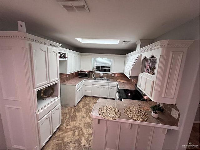 3404 Robin Ave, Pharr, TX 78577 - kitchen with appliances with stainless steel finishes, a sink, backsplash, white cabinets, and a peninsula