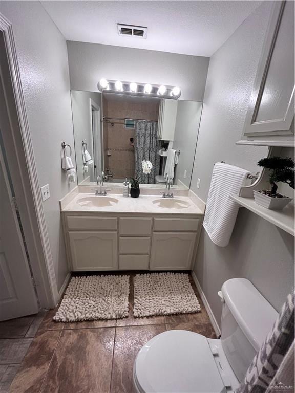3404 Robin Ave, Pharr, TX 78577 - full bathroom featuring toilet, a tile shower, double vanity, and baseboards