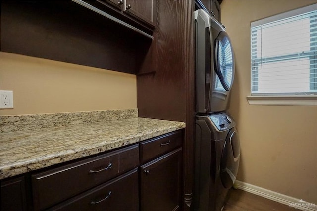 laundry room featuring cabinets and stacked washer and dryer