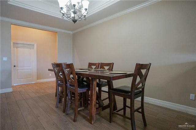 dining area with a notable chandelier, crown molding, and hardwood / wood-style floors