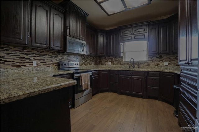 kitchen with sink, appliances with stainless steel finishes, dark brown cabinetry, light hardwood / wood-style floors, and decorative backsplash