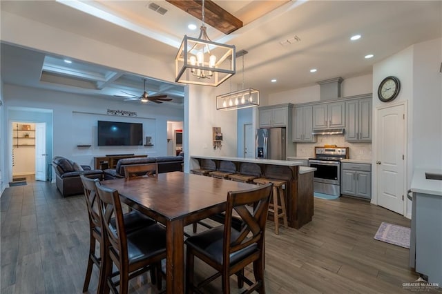 dining room featuring ceiling fan with notable chandelier, dark wood-style flooring, beam ceiling, and visible vents