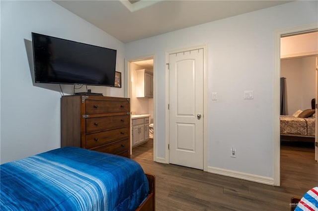 bedroom with dark wood-style flooring, baseboards, ensuite bathroom, and lofted ceiling