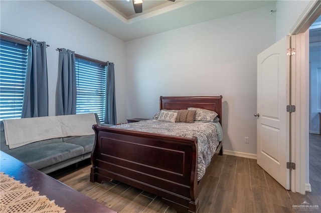 bedroom with baseboards, ceiling fan, wood finished floors, and a raised ceiling