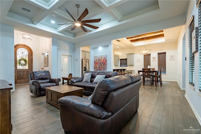 living area with visible vents, wood finished floors, a tray ceiling, a ceiling fan, and coffered ceiling