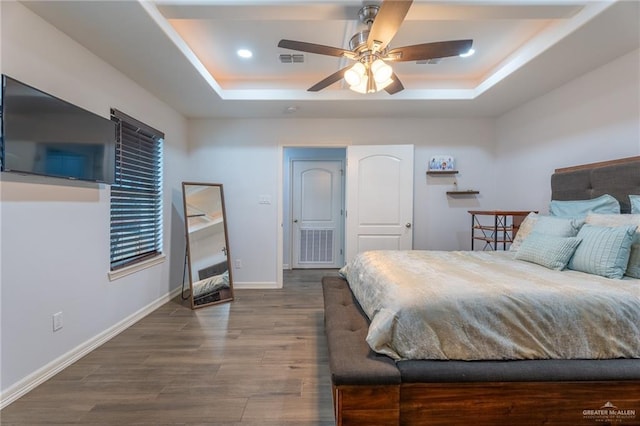 bedroom featuring visible vents, baseboards, ceiling fan, dark wood-style floors, and a raised ceiling