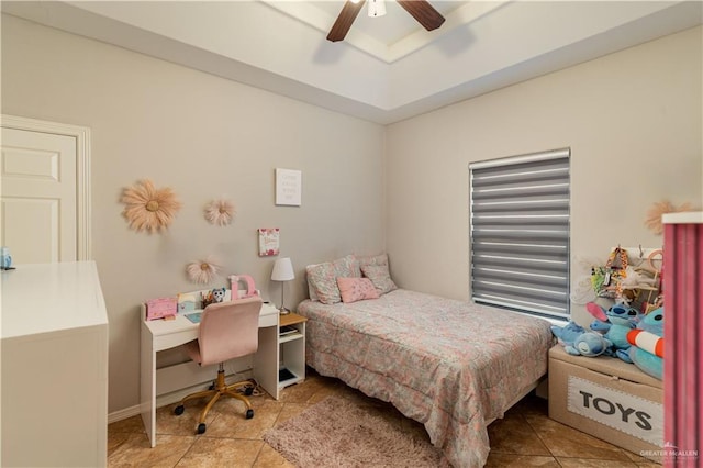 bedroom featuring light tile patterned floors, a raised ceiling, and a ceiling fan