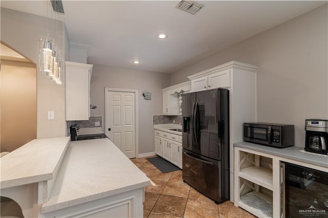 kitchen featuring beverage cooler, black appliances, pendant lighting, and white cabinets