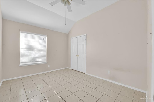 unfurnished room with vaulted ceiling, light tile patterned floors, a ceiling fan, and baseboards