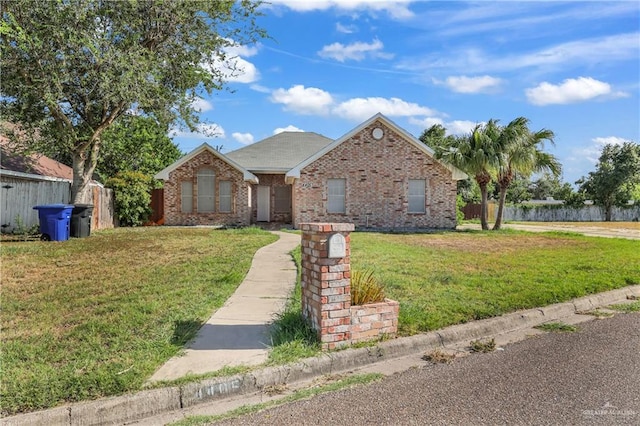 ranch-style house featuring fence, a front lawn, and brick siding