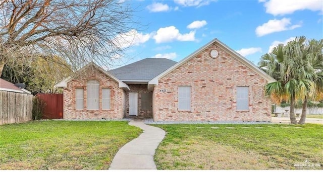 single story home featuring brick siding, fence, and a front lawn