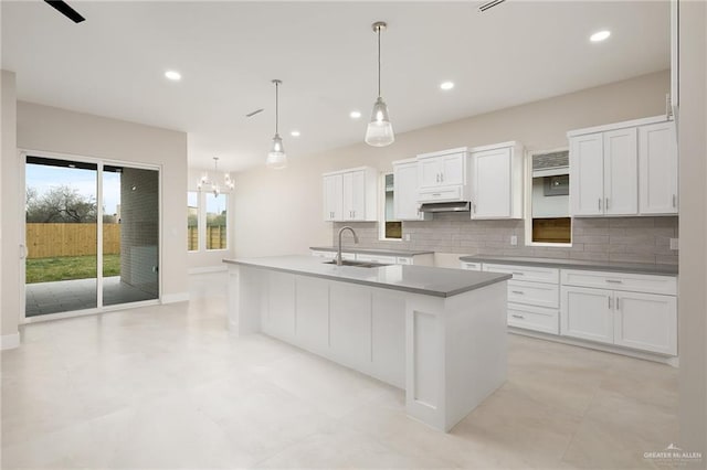 kitchen with sink, hanging light fixtures, a center island with sink, and white cabinets