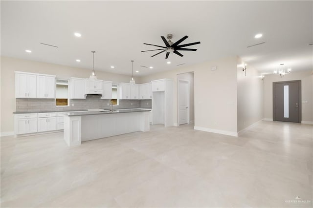 kitchen with tasteful backsplash, a kitchen island with sink, sink, and white cabinets