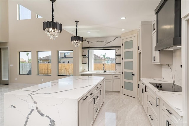 3905 Tierra Escondida, Weslaco, TX 78596 - kitchen with an inviting chandelier, wall chimney range hood, a kitchen island, marble finish floor, and black electric stovetop