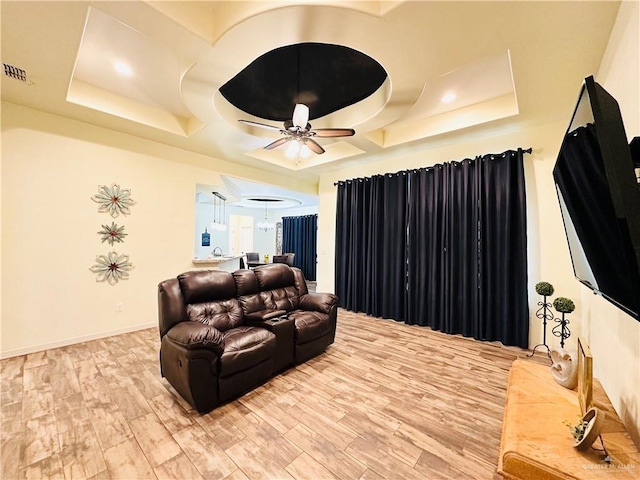 home theater room featuring light wood finished floors, ceiling fan, visible vents, and baseboards