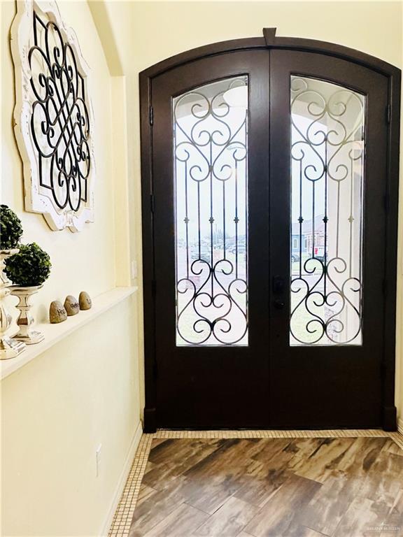 entrance foyer featuring arched walkways, french doors, wood finished floors, and baseboards