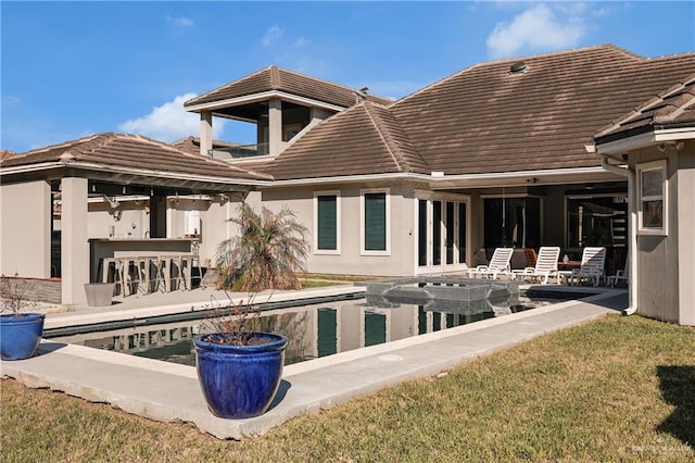 rear view of house with outdoor dry bar, a patio, and a tiled roof