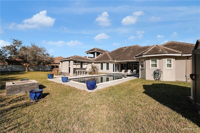 back of house featuring a patio, an outdoor pool, fence, a lawn, and stucco siding